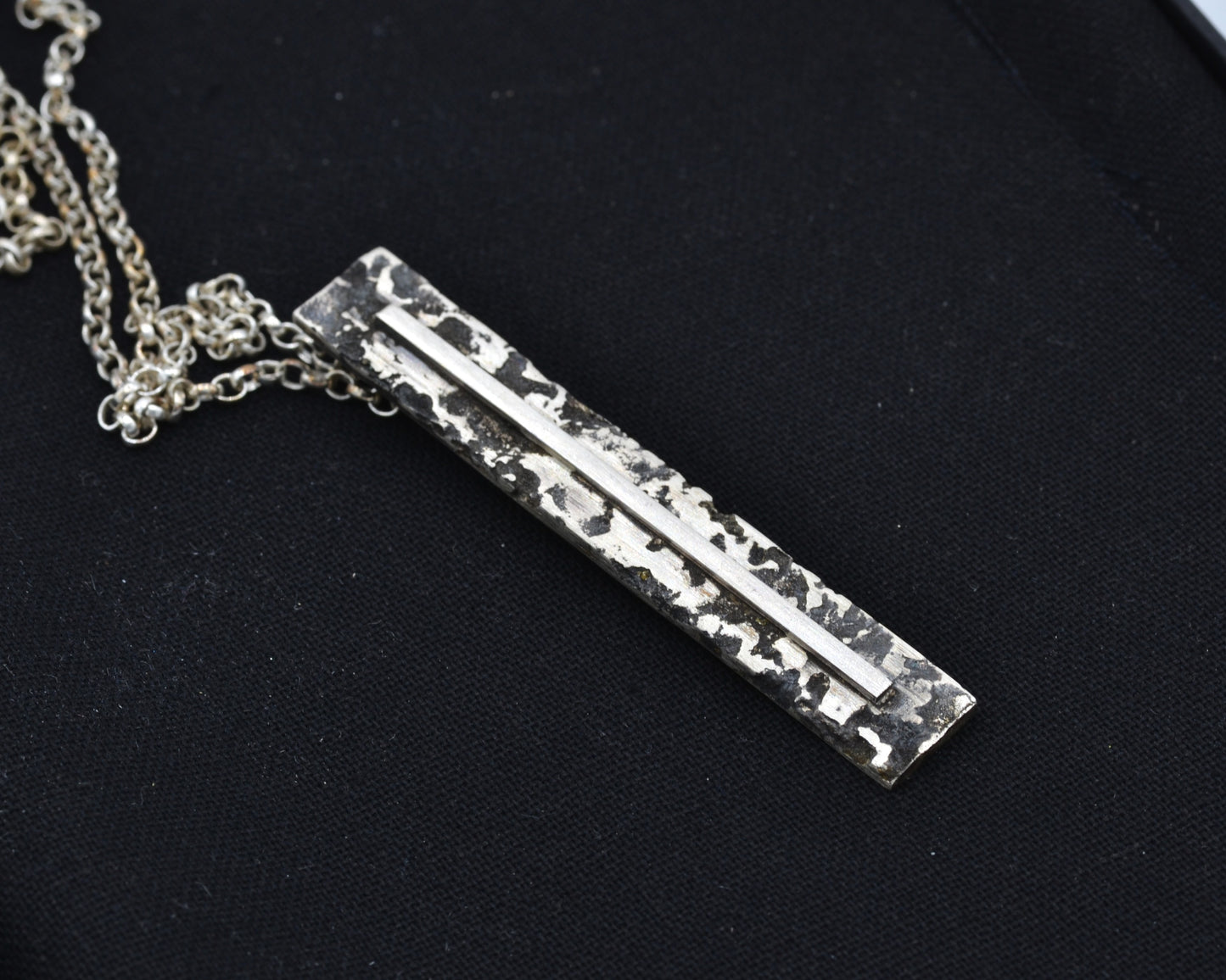 Sculptural silver necklace with rough finish, avant-garde aesthetic