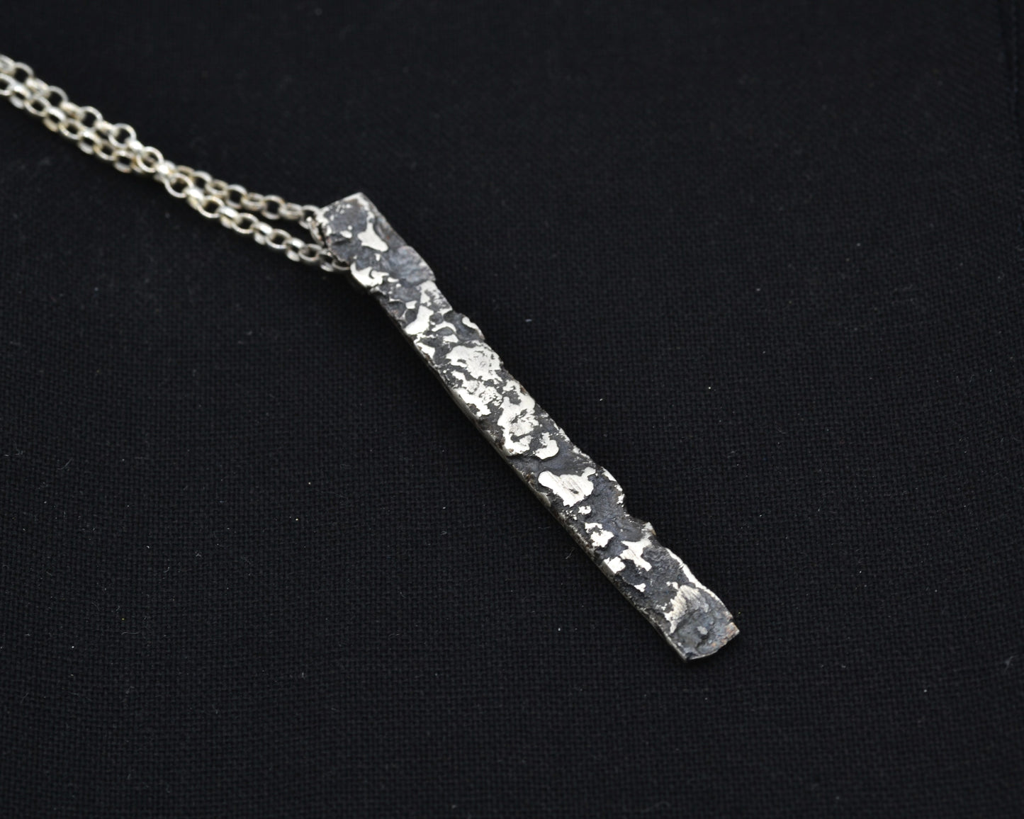 Minimalist, avantgarde silver pendant necklace with a melted, oxidized, raw finish.