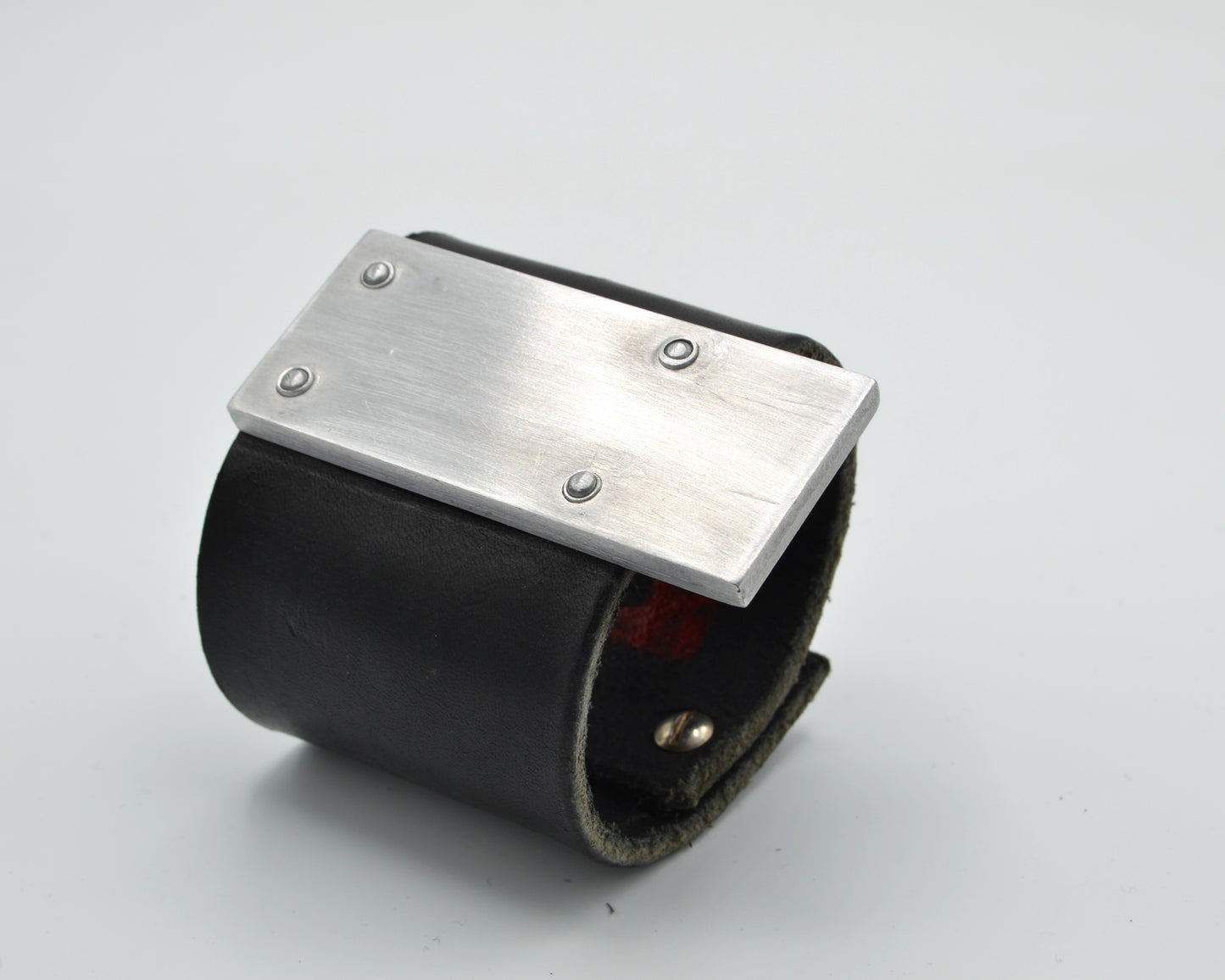 avantgarde, brutalist leather bracelet with aluminum plate mounted on top.