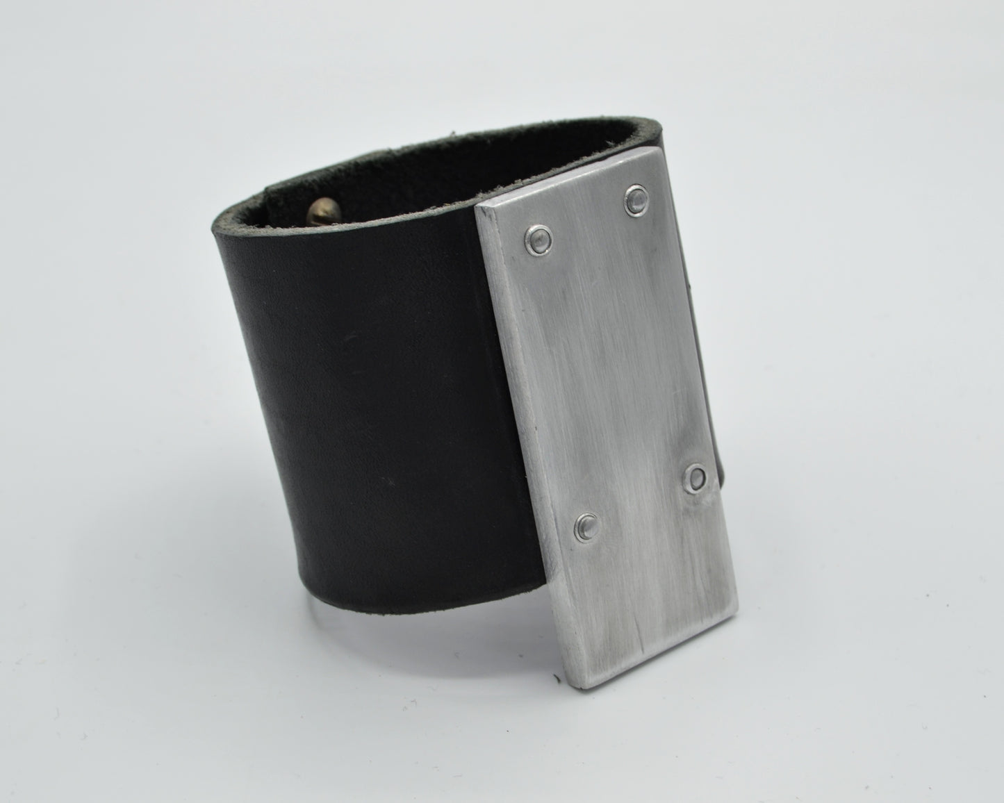 avantgarde, brutalist leather bracelet with aluminum plate mounted on top.