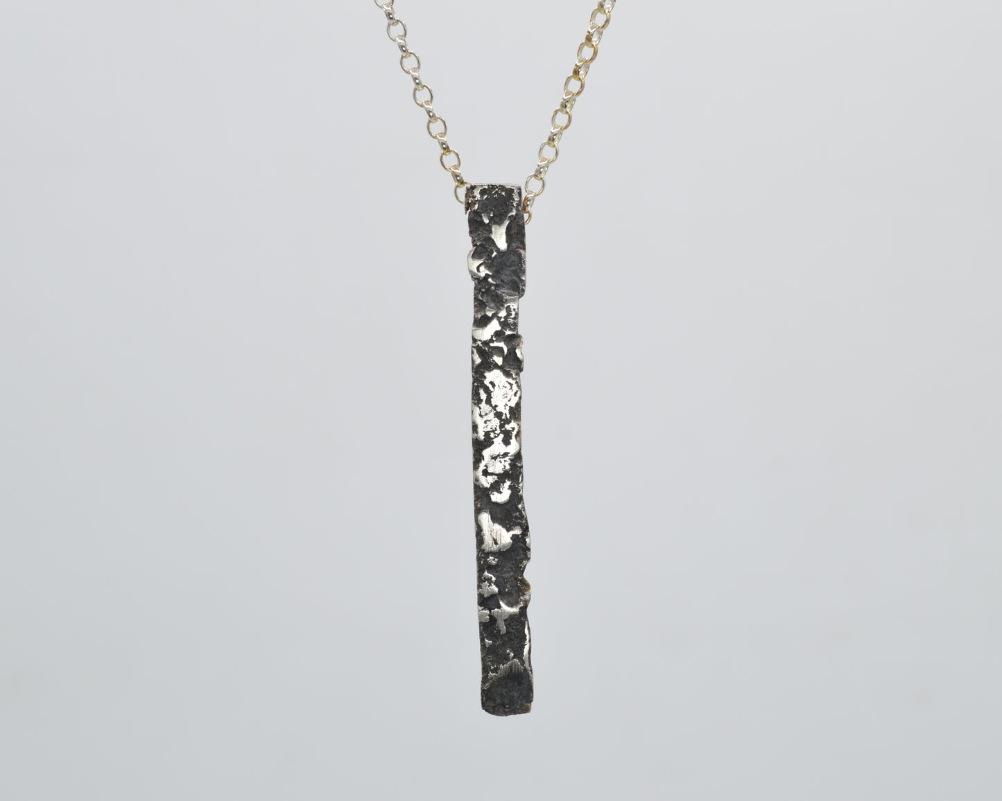 Minimalist, avantgarde silver pendant necklace with a melted, oxidized, raw finish.