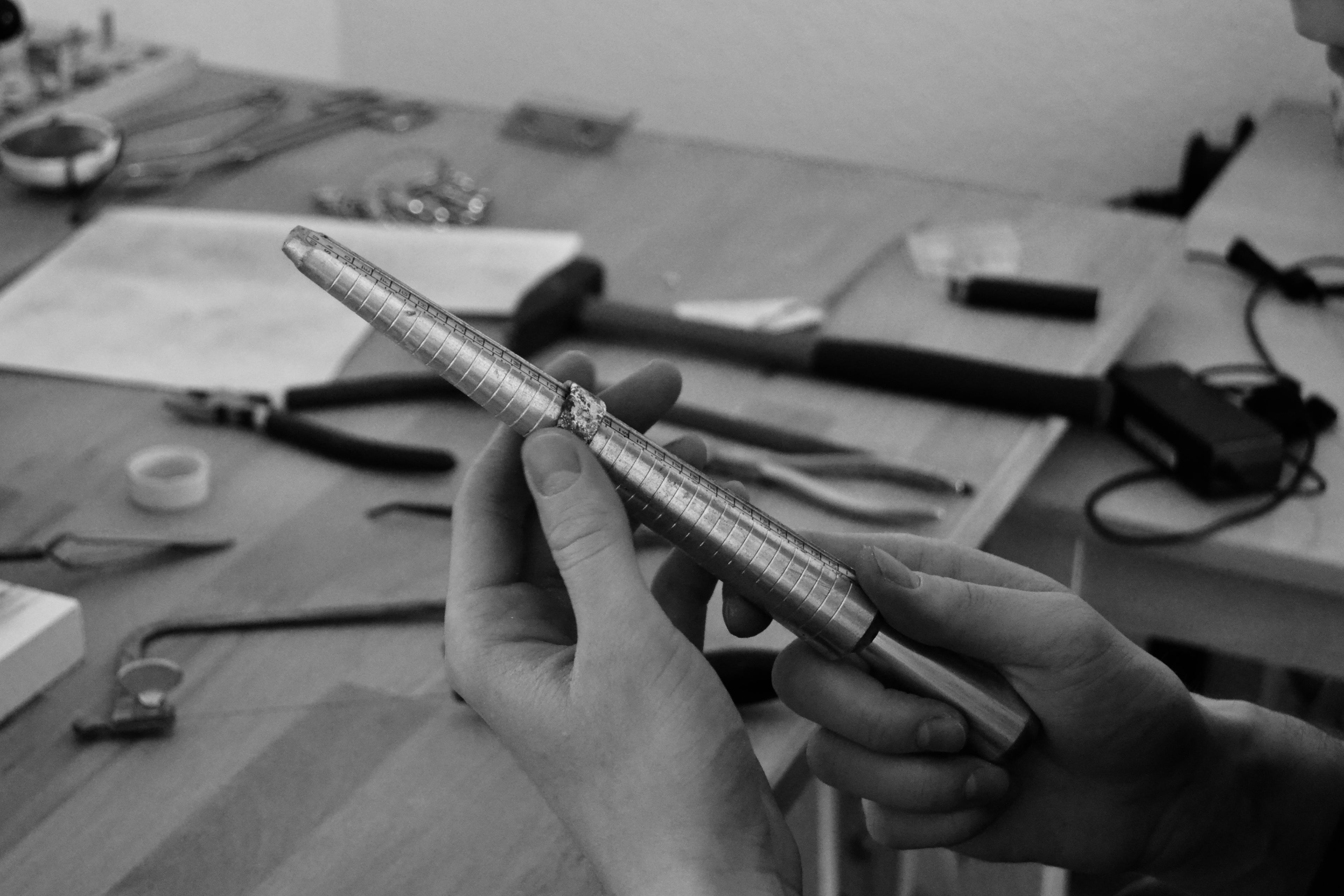 Two hands holding a ring sizer in a jewelry workshop – handmade silver ring in the process of being created, 2819 Jewelry, Leipzig.