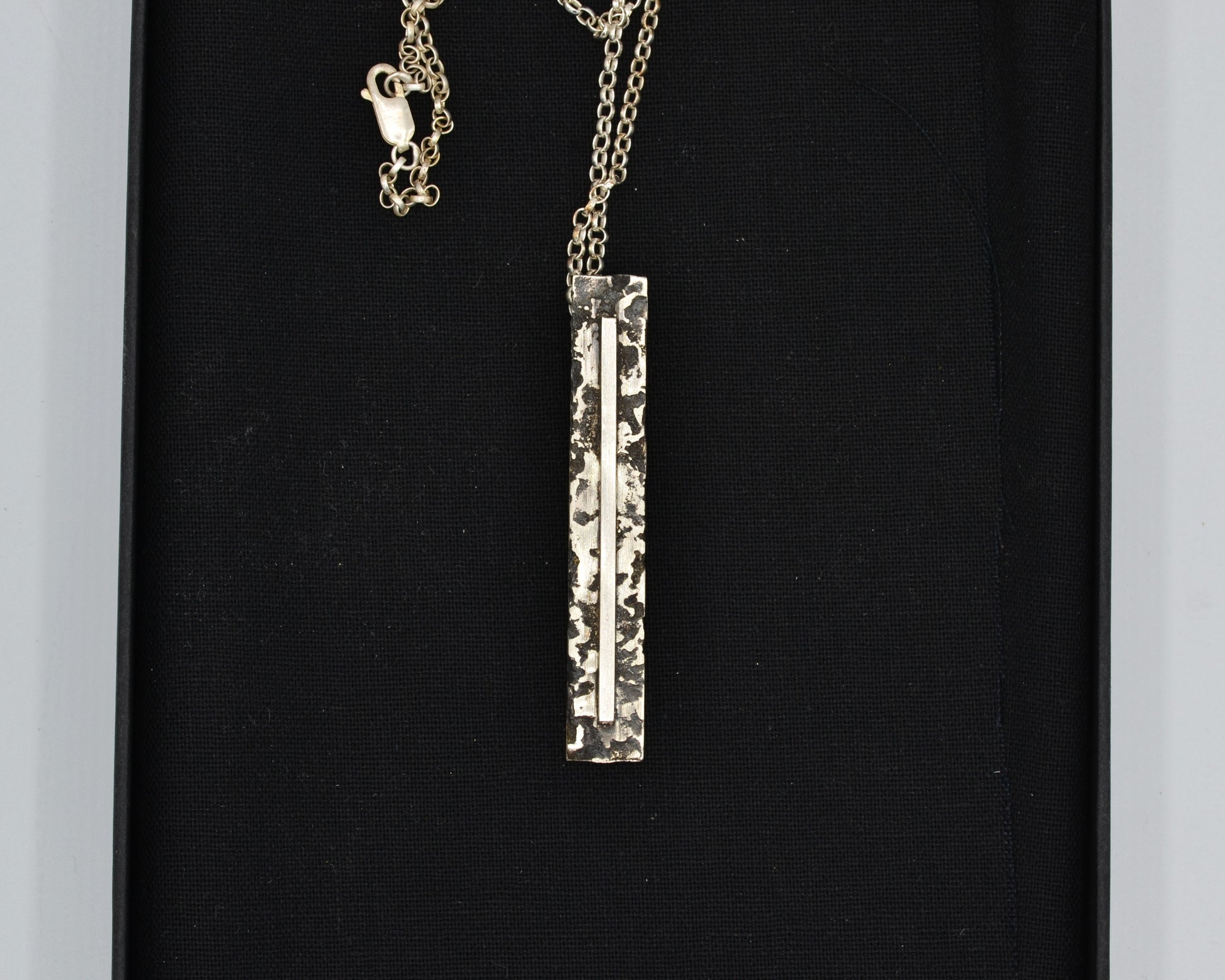 Sculptural silver necklace with rough finish, avant-garde aesthetic