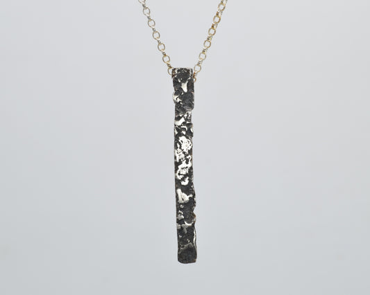 Minimalist, avantgarde silver pendant necklace with a melted, oxidized, raw finish.